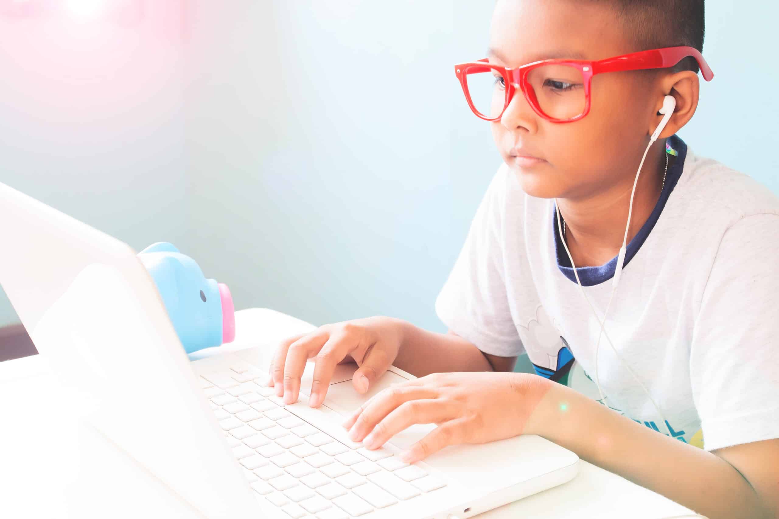 enfant portant des lunettes rouges et utilisant un ordinateur